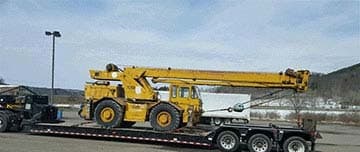 Rough-terrain truck crane secured on a lowboy trailer